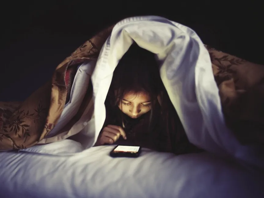 طفل يستخدم هاتفاً ذكياً في فراشه - Bloomberg