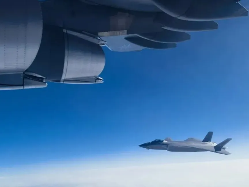 مقاتلة شبحية صينية من طراز J-20 ترافق طائرة شحن عسكري من طراز Y-20 فوق شينيانج. 23 نوفمبر 2023 - AFP