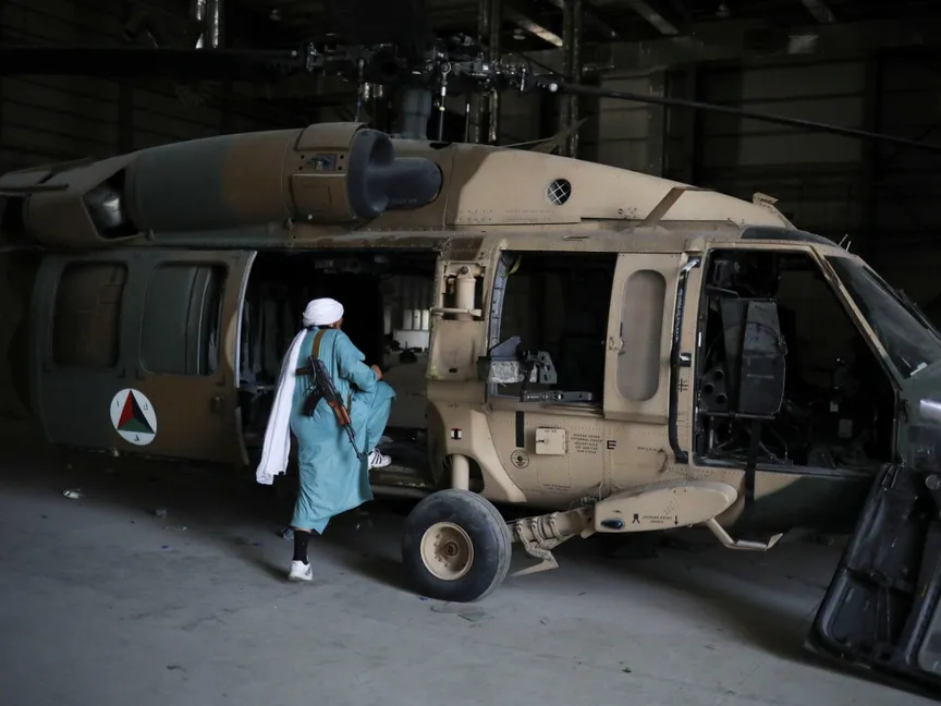 عنصر تابع لحركة طالبان يركب طائرة هليكوبتر في قاعدة باجرام الجوية التي تقع على مسافة 50 كيلومتراً من العاصمة كابول. 23 سبتمبر 2021 - REUTERS