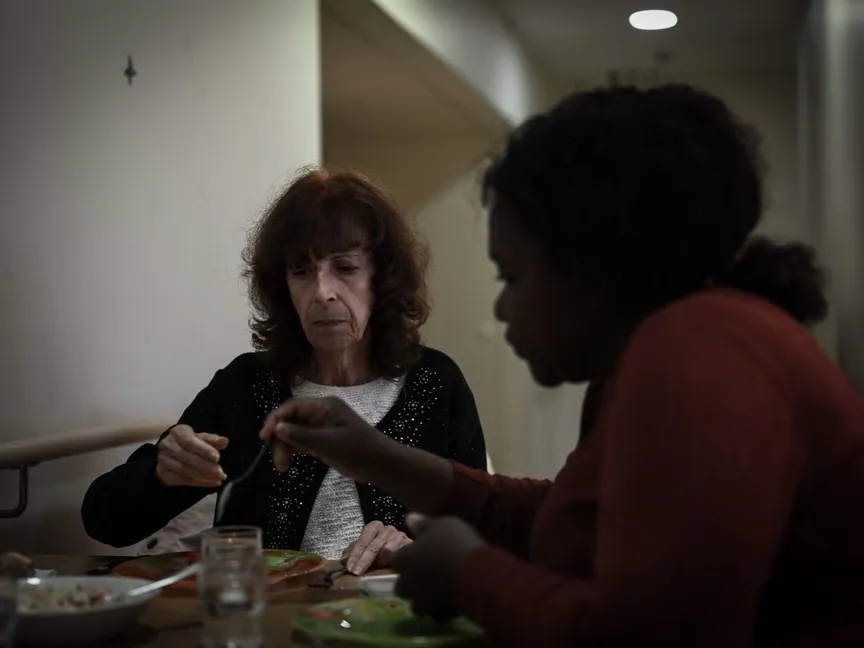 موظفة رعاية صحية تقدم المساعدة لمريضة مصابة بمرض ألزهايمر أثناء وقت الغداء في أحد أماكن المعيشة في منشأة مخصصة لمرضى ألزهايمر في داكس جنوب غرب فرنسا. 30 نوفمبر 2023 - AFP