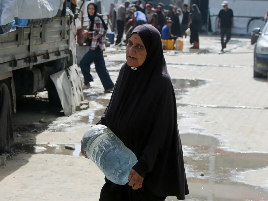 امرأة فلسطينية نازحة بسبب الهجوم العسكري الإسرائيل تحمل قارورة مياه في خان يونس. جنوب قطاع غزة في 19 أغسطس 2025 - reuters