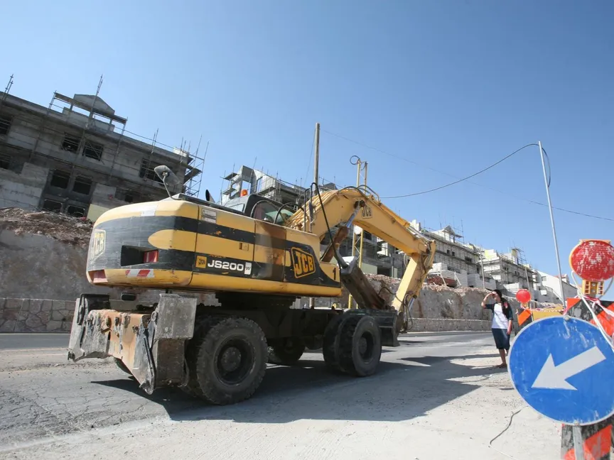 آلية بناء إسرائيلية تمر عبر وحدات سكنية جديدة في مستوطنة إسرائيلية بالضفة الغربية - AFP - AFP