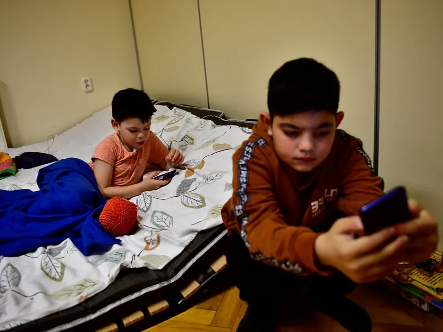 أطفال يلعبون بهواتفهم في أحد مخيمات اللاجئين الأوكرانيين في بودابست. 27 فبراير 2022 - REUTERS