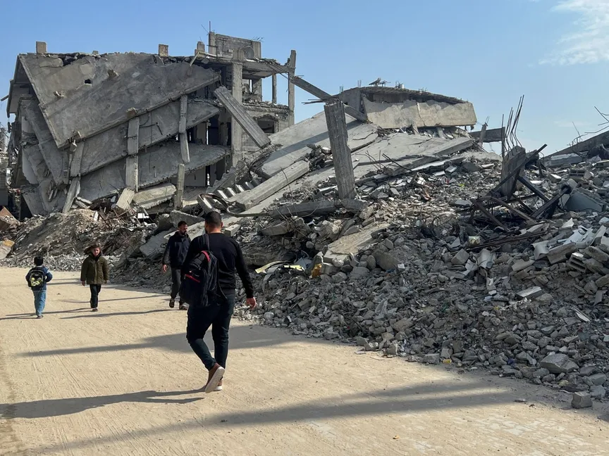 فلسطينيون يسيرون وسط أنقاض المنازل المدمرة في خان يونس جنوب قطاع غزة. 6 مارس 2025 - REUTERS