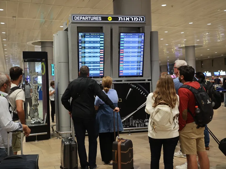 مسافرون ينظرون إلى شاشة تعرض الرحلات المغادرة في مطار بن جوريون بتل أبيب عقب تعليق الحركة الجوية بعد هجوم حركة حماس. 7 أكتوبر 2023 - AFP