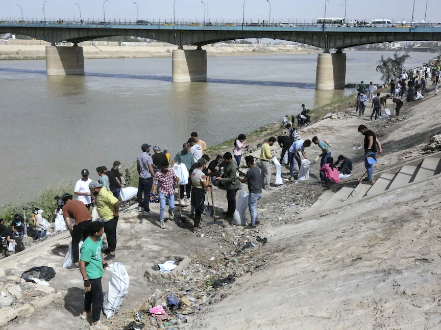 متطوعون عراقيون شبان يشاركون في حملة تنظيف على ضفة نهر دجلة في منطقة الأعظمية بالعاصمة بغداد - 11 مارس 2022 - AFP