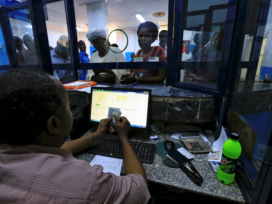 صراف بأحد البنوك السودانية في العاصمة الخرطوم يحصي عدداً من الدولارات الأميركية - REUTERS