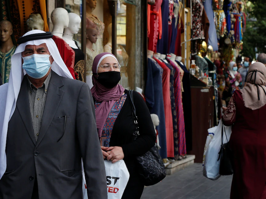 أشخاص يرتدون الكمامات يسيرون في أحد شوارع وسط العاصمة الأردنية عمّان - REUTERS