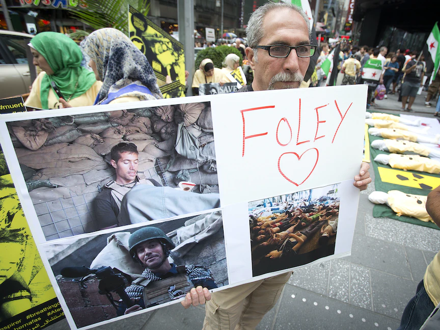 رجل يحمل لافتة تخليداً لذكرى الصحافي الأميركي جيمس فولي خلال مظاهرة في تايمز سكوير، نيويورك الولايات المتحدة - 22 أغسطس 2014. - REUTERS