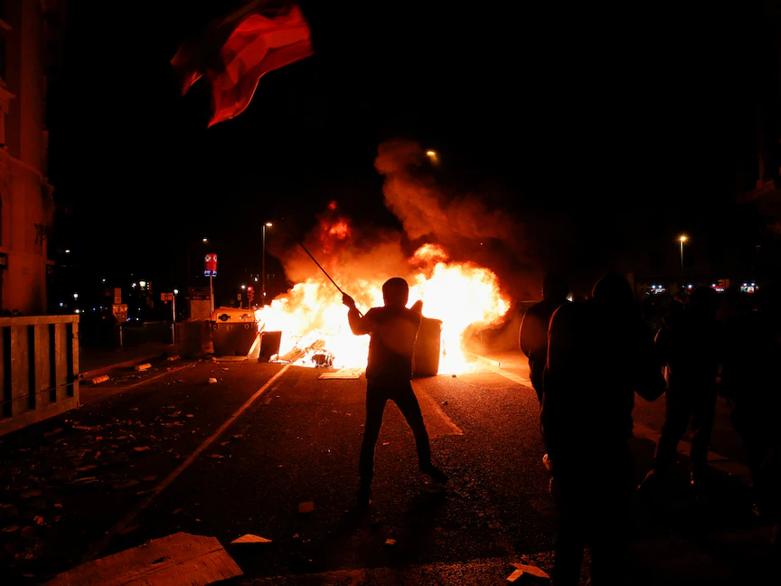 متظاهر أمام نيران مشتعلة خلال مظاهرات عنيفة في إقليم كتالونيا احتجاجاً على سجن مغني الراب الإسباني بابلو هاسل - REUTERS