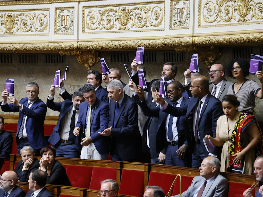 نواب فرنسيون يلوّحون بنص الدستور خلال مناقشة اقتراح قانون يلغي رفع سنّ التقاعد إلى 64 عاماً في البرلمان. 8 يونيو 2023 - AFP