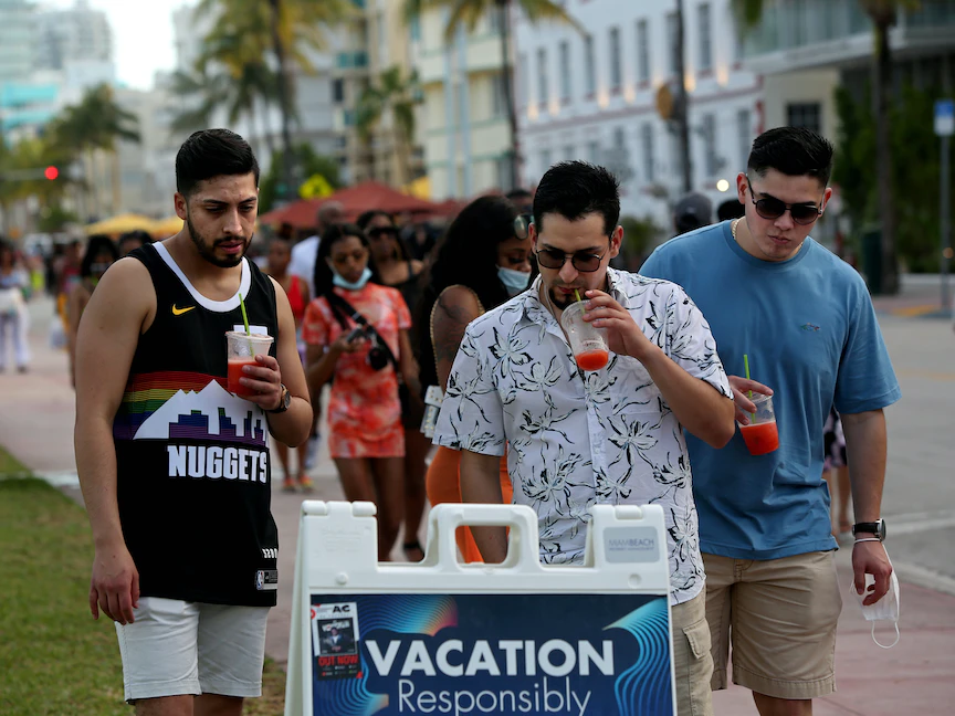 شباب يقرؤون احتياطات السلامة العامة أثناء وجودهم في ساوث بيتش، ميامي - REUTERS