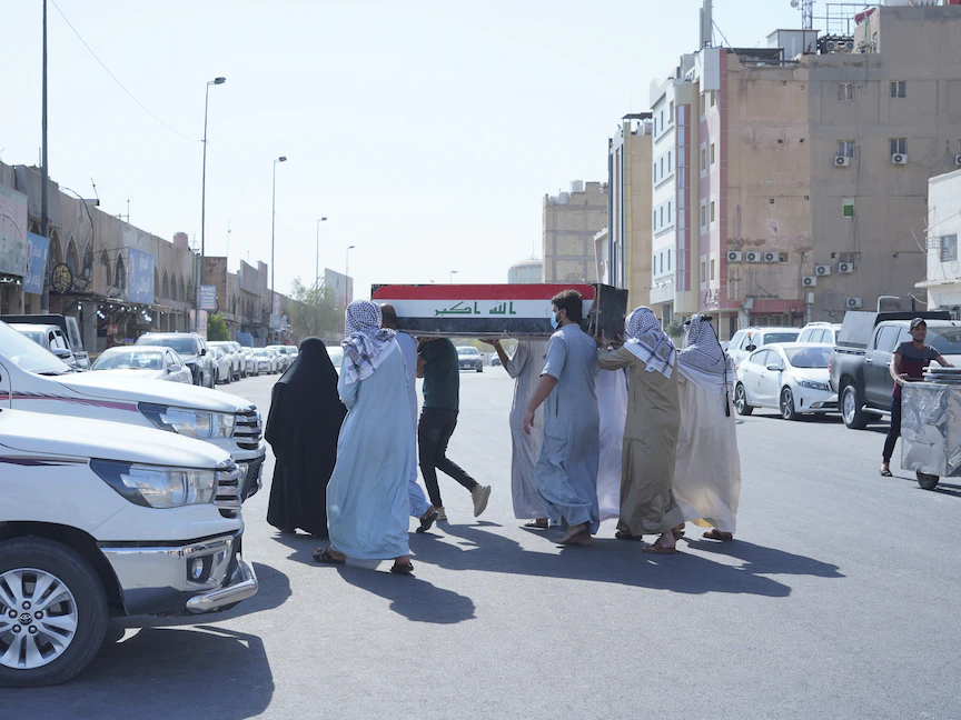 عدد من الأشخاص يحملون جثمان أحد ضحايا حريق مستشفى ذي قار جنوبي العراق - 13 يوليو 2021 - Anadolu Agency via Getty Images