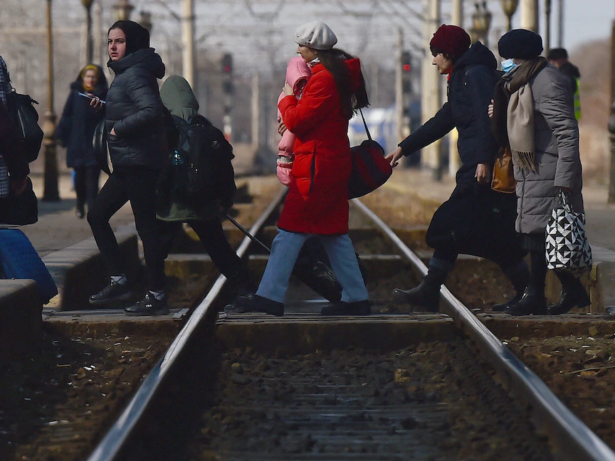 سيدة أوكرانية لاجئة تحمل طفلها أثناء عبور سكة القطار قبل التوجه إلى رومانيا- 17 مارس 2022 - REUTERS