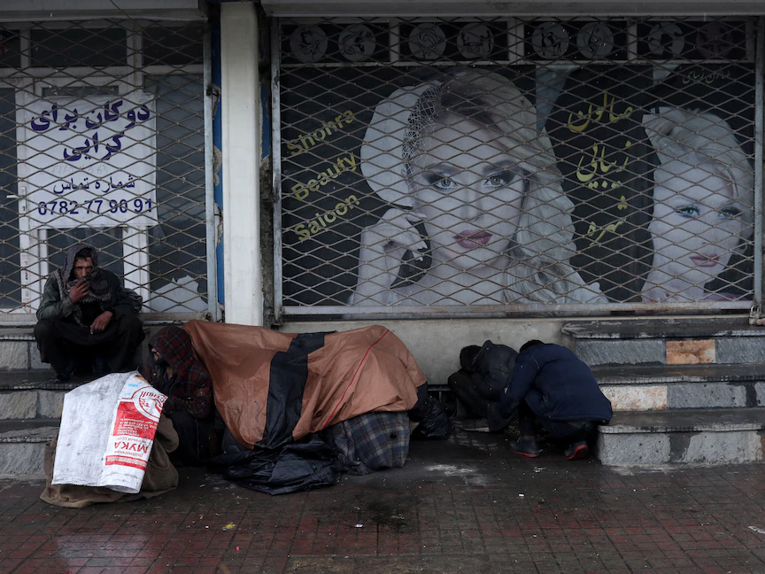 أشخاص يغطون أنفسهم وهم يجلسون أمام صالون تجميل في كابول، أفغانستان. 3 يناير 2022 - REUTERS