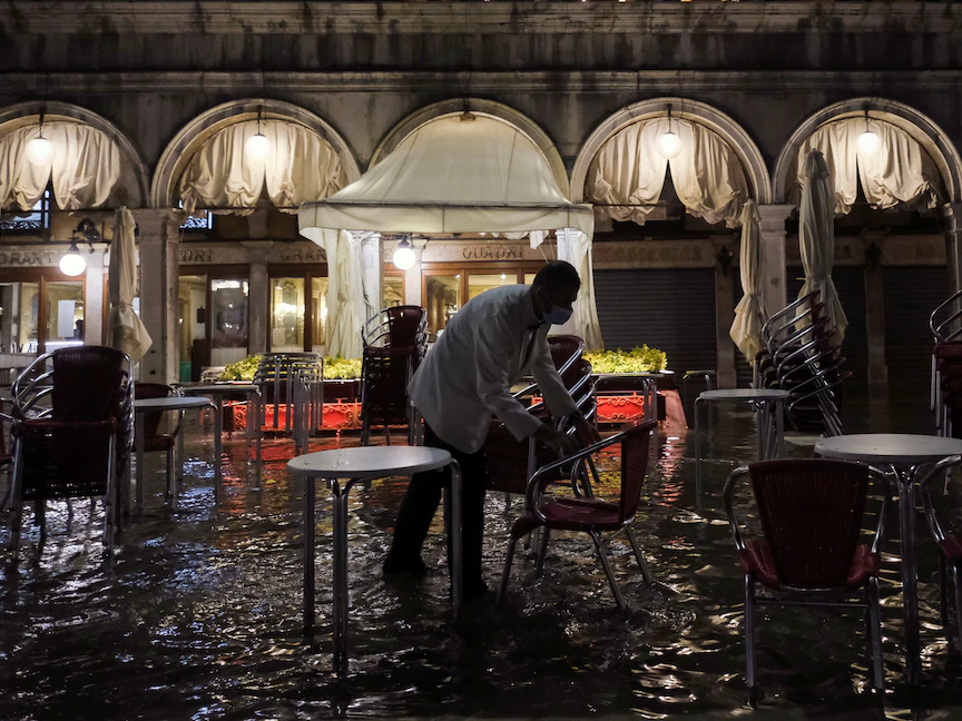عامل يغلق مطعماً في ساحة سان ماركو في البندقية التي غمرتها المياه، إيطاليا، 8 أغسطس 2021 - REUTERS