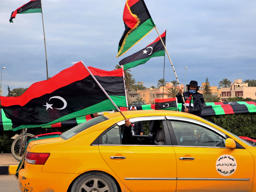 ليبيون في وسط العاصمة طرابلس يحملون أعلام بلادهم، 25 فبراير 2021 - AFP