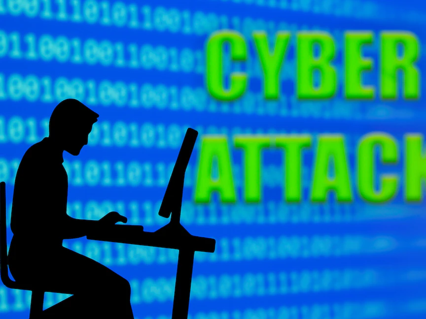 صورة توضيحية لرجل يعمل على الكمبيوتر بجانب جملة "هجوم إلكتروني" - REUTERS