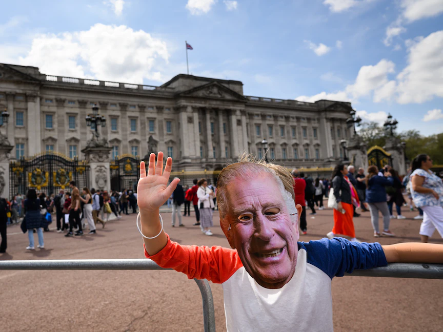 شخص يرتدي قناعاً لملك بريطانيا تشارلز الثالث خارج قصر باكنجهام في وسط لندن. 7 مايو 2023 - AFP