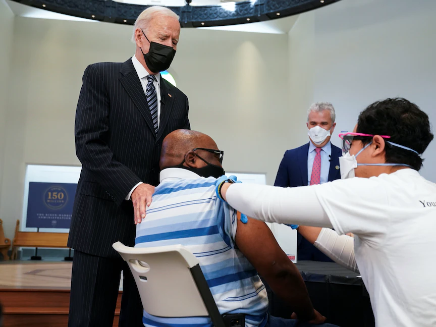 الرئيس الأميركي جو بايدن يضع يده على كتف رجل خلال زيارته موقع التطعيم ضد فيروس كورونا في فيرجينيا - 6 أبريل 2021 - REUTERS