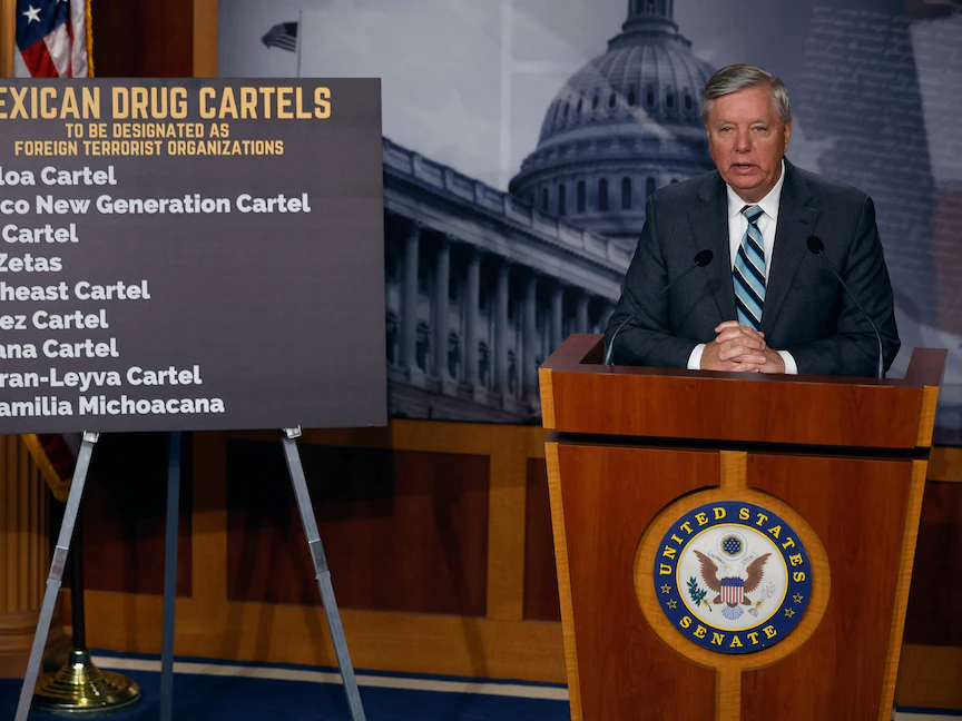 السيناتور الأميركي ليندساي جراهام خلال مؤتمر صحافي وإلى جواره قائمة بأسماء عصابات المخدرات الأميركية لدى دعوته لتقديم تشريع لتصنيفها "مجموعات إرهابية"، واشنطن. 8 مارس 2023 - Getty Images