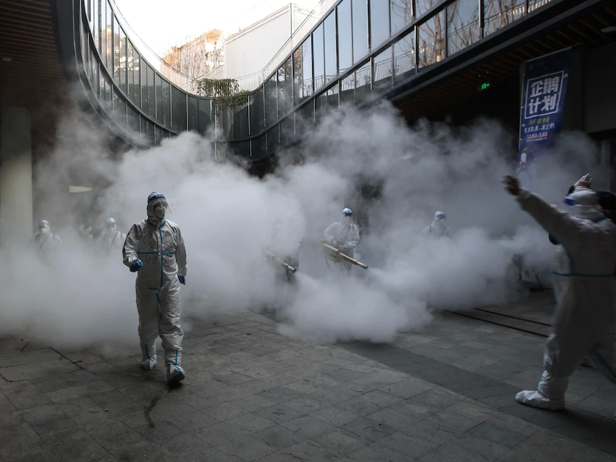 موظفون يرتدون معدات الحماية الشخصية خلال عمليات تعقيم خارج مركز تسوق بمدينة شيان الصينية - 11 يناير 2022 - AFP