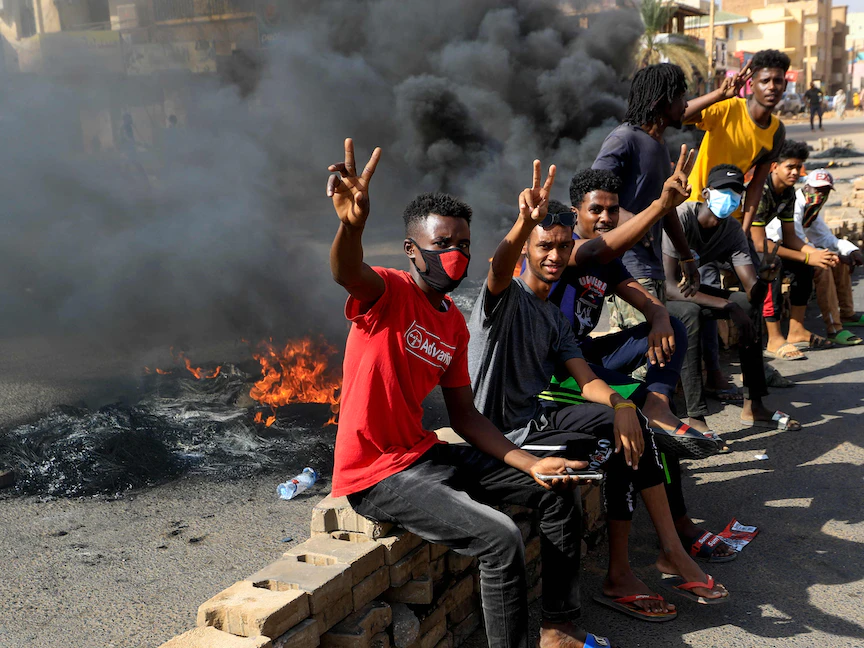 متظاهرون سودانيون يرفعون إشارة النصر وهم يحرقون الإطارات لإغلاق طريق في شارع الستين بالعاصمة الخرطوم تنديداً باعتقالات الجيش لأعضاء الحكومة السودانية- 25 أكتوبر 2021. - AFP