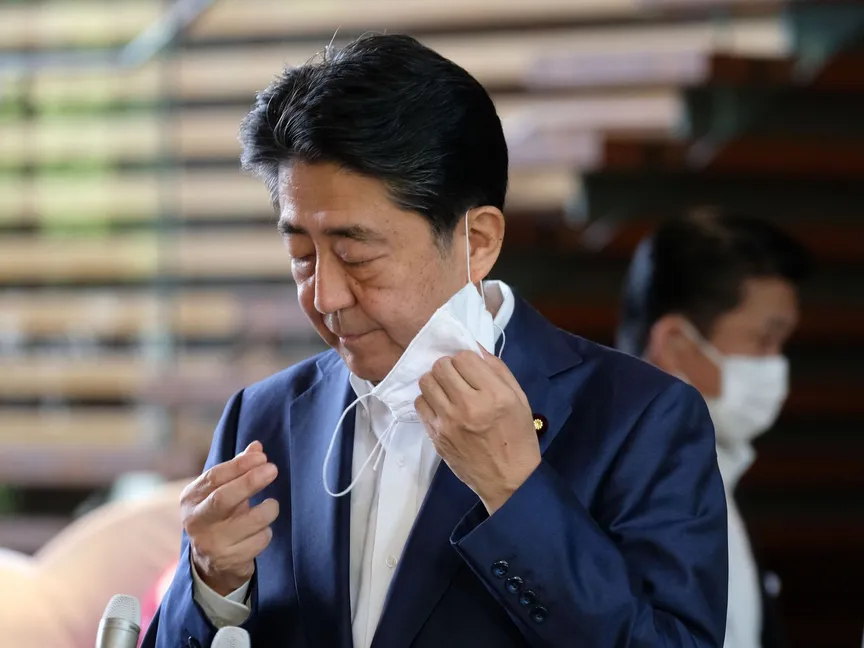 رئيس الوزراء الياباني شينزو آبي ينزع الكمامة قبل أن يصرح للصحافيين بعد خروجه من المستشفى اليوم الاثنين - AFP