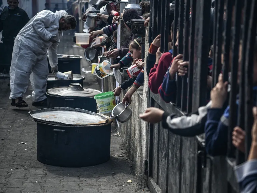 أطفال فلسطينيون خلف أحد الحواجز في رفح جنوبي قطاع غزة يصطفون للحصول على الطعام. 25 فبراير 2024 - AFP