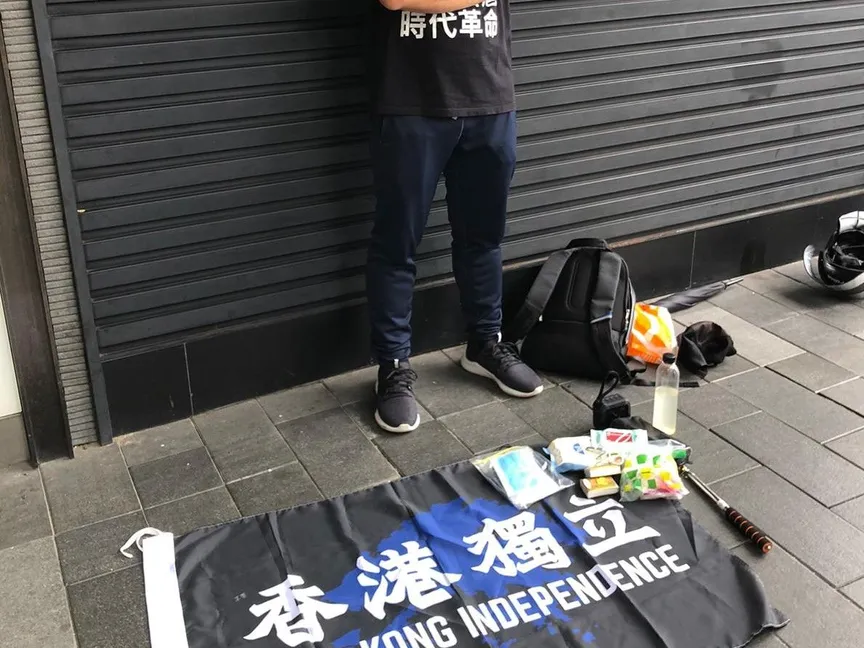 صورة نشرتها شرطة هونغ كونغ للموقوف من دون إظهار وجهه وأمامه علم الاستقلال - Twitter