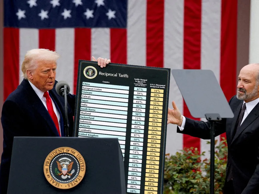 الرئيس الأميركي دونالد ترمب يحمل خريطة توضح الرسوم الجمركية التي فرضها على الدول بينما يلقي كلمة في البيت الأبيض بالعاصمة واشنطن- 2 أبريل 2025 - Reuters