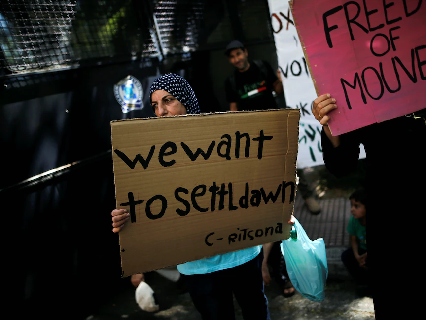 لاجئة سورية ترفع لافتة خلال تظاهرة أمام السفارة الألمانية في أثينا - 2 أغسطس 2017 - REUTERS