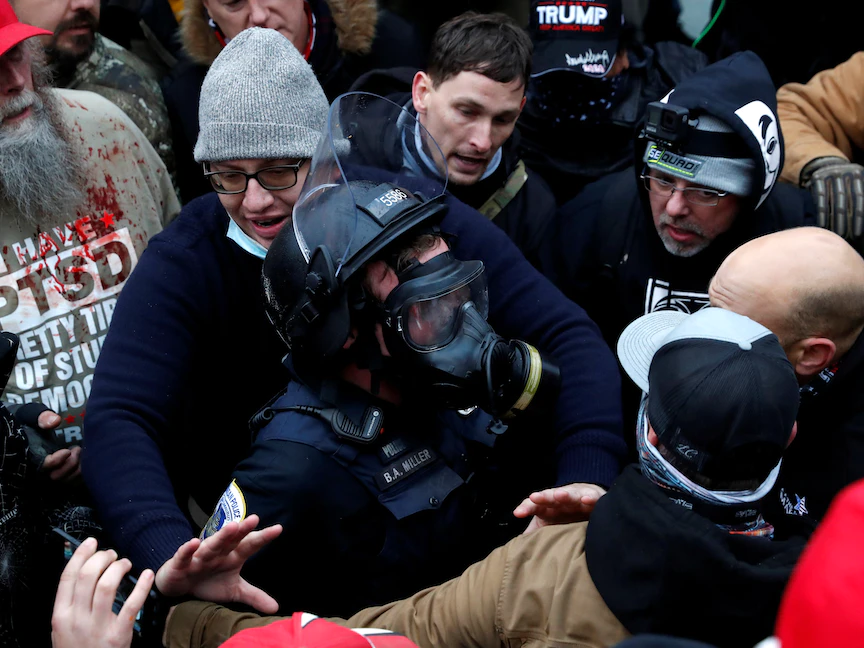 أحد أفراد الشرطة وحوله عدد من أنصار الرئيس الأميركي دونالد ترمب داخل مقر الكونغرس - REUTERS