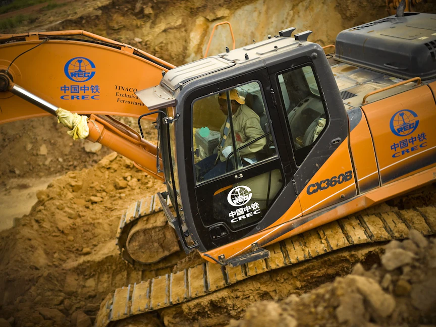 شعار شركة صينية على جرافة يقودها عامل بناء خلال مشروع للسكك الحديد في فنزويلا، 22 أغسطس 2012 - Bloomberg