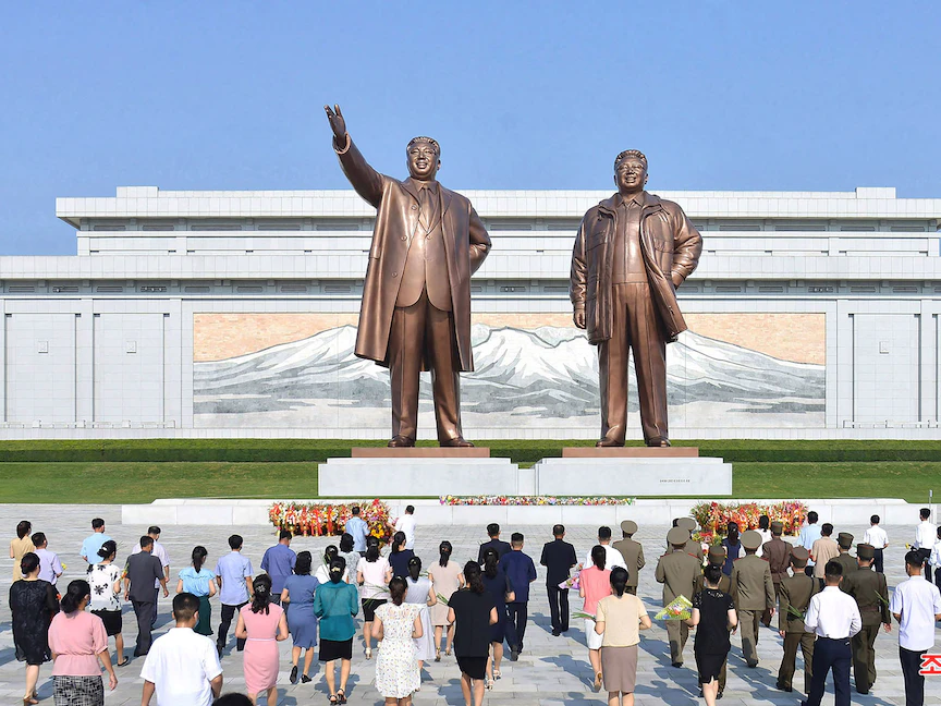 يقدمون الزهور لتمثالي الرئيس السابق كيم إيل سونغ والرئيس السابق كيم جونغ إيل، في مانسوداي في بيونغ يانغ، للاحتفال بالذكرى الـ 68 لانتهاء الحرب الكورية. 27 يوليو 2021 - AFP