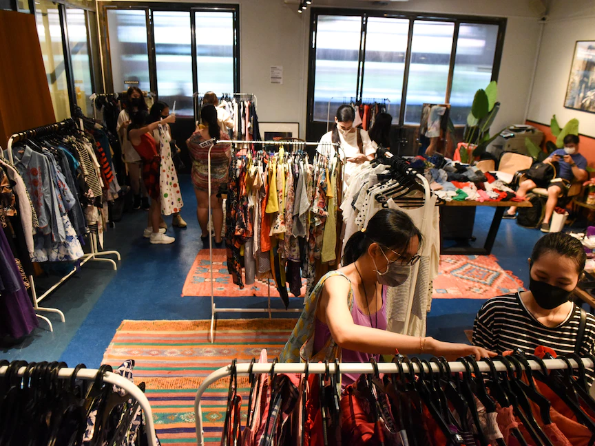 متسوقون وهم يفحصون الملابس المستعملة في حدث تبادل منبثق نظمته مجموعة من المتطوعين في سنغافورة. - AFP