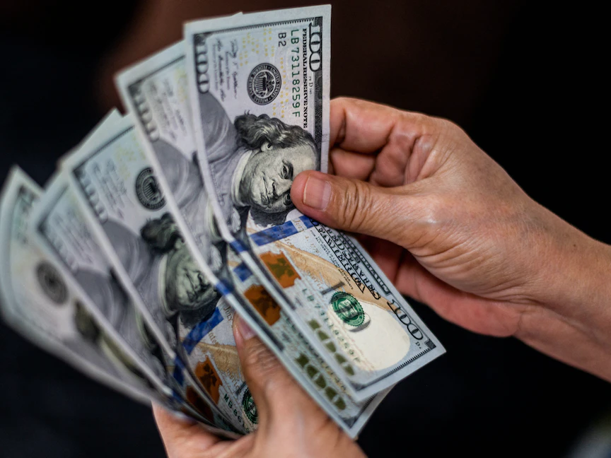 شخص يعد النقود بالدولار الأميركي في متجر صرافة في مانيلا- الفلبين- 21 أكتوبر 2022. - REUTERS