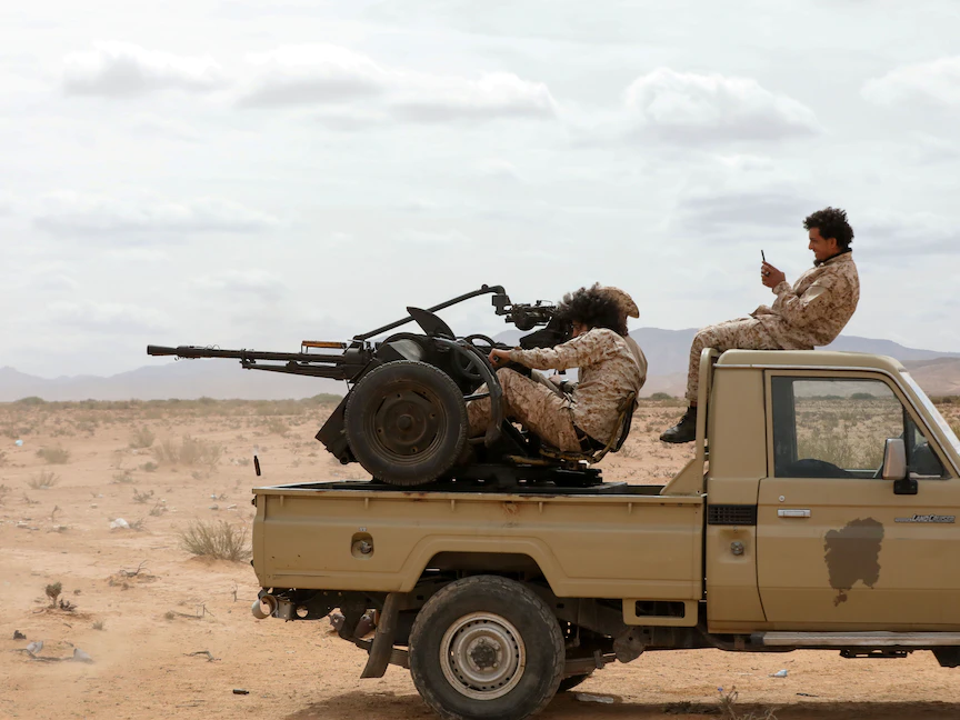 عناصر من حرس المنشآت النفطية في ليبيا يستقلون شاحنة صغيرة في بلدة بئر الغنم جنوب غرب طرابلس، 22 مارس 2021 - REUTERS