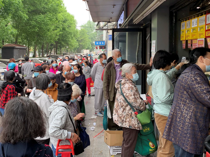 مئات الصينيين يرتدون الكمامات ويقفون في طوابير لشراء المواد الغذائية في منطقة تشاويانج في بكين. 25 أبريل 2022 - REUTERS
