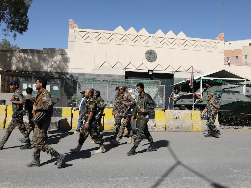 مقاتلون من جماعة الحوثي في اليمن يمرون أمام مقر السفارة الأميركية المغلق في صنعاء - 18 يناير 2021 - REUTERS