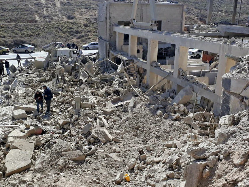 أشخاص يتفقدون مبنى مدمراً في أعقاب الضربات الصاروخية الإسرائيلية قبل الفجر بالقرب من العاصمة دمشق. في 7 مارس 2022. - AFP