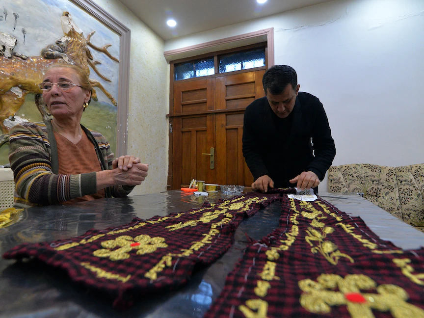 وضع اللمسات الأخيرة بخيوط ذهبية على وشاح سيقدم هدية للبابا فرنسيس أثناء زيارته إلى بلدة قرقوش في العراق - AFP