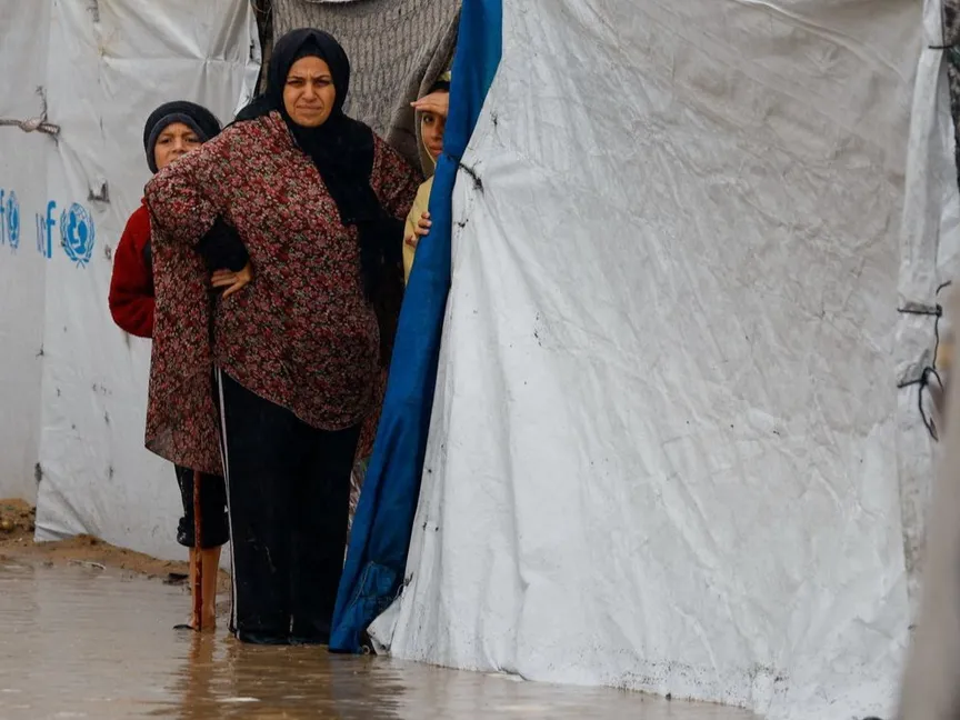 عائلة فلسطينية نازحة تراقب مياه الأمطار التي أغرقت المخيمات في منطقة النصيرات بشمال قطاع غزة. 12 ديسمبر 2025 - REUTERS