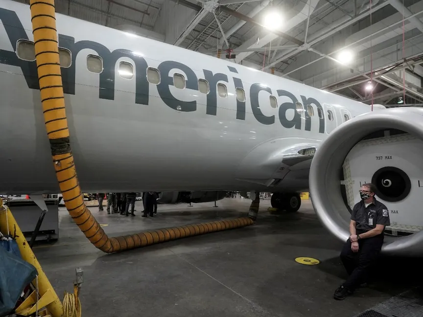 عامل في الخطوط الجوية الأميركية يجلس على غطاء محرك طائرة بوينج 737 ماكس في ورشة صيانة في تولسا بأوكلاهوما في الولايات المتحدة. 2 ديسمبر 2020 - REUTERS