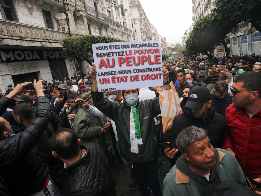 متظاهر يحمل لافتة كتب عليها "أنتم عاجزون، سلموا السلطة للشعب، دعونا نبني دولة القانون" خلال تظاهرة لإحياء الذكرى الثانية للحراك في العاصمة الجزائر - 22 فبراير 2021 - REUTERS