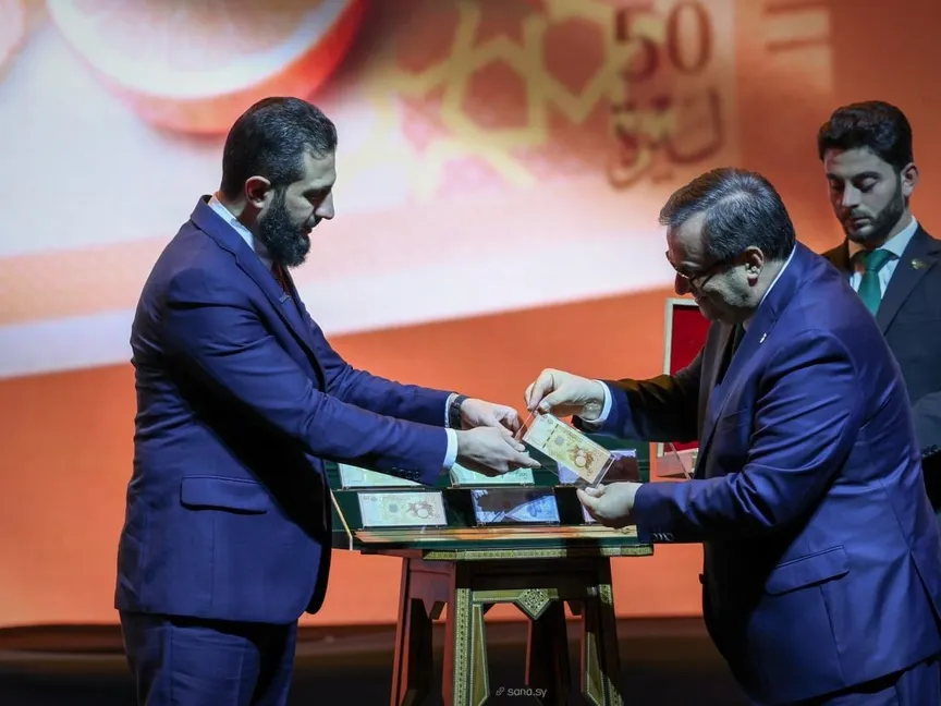 الرئيس السوري أحمد الشرع وحاكم المصرف المركزي عبد القادر الحصرية خلال حفل إطلاق العملة السورية الجديدة في دمشق. 29 ديسمبر 2025 - سانا
