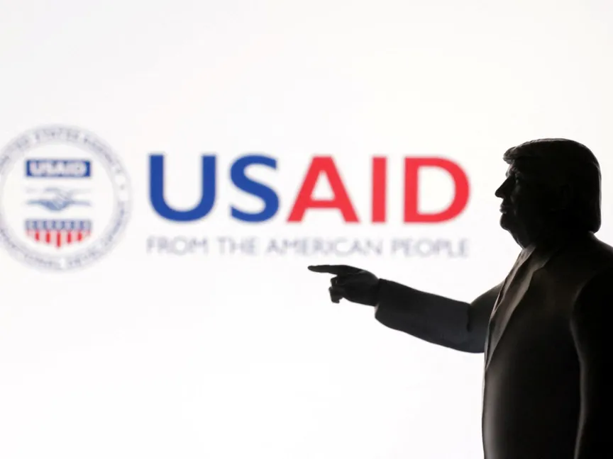 نموذج مصغر مطبوع ثلاثي الأبعاد للرئيس الأميركي دونالد ترمب مع شعار الوكالة الأميركية للتنمية الدولية في الخلفية. 23 أبريل 2025 - REUTERS