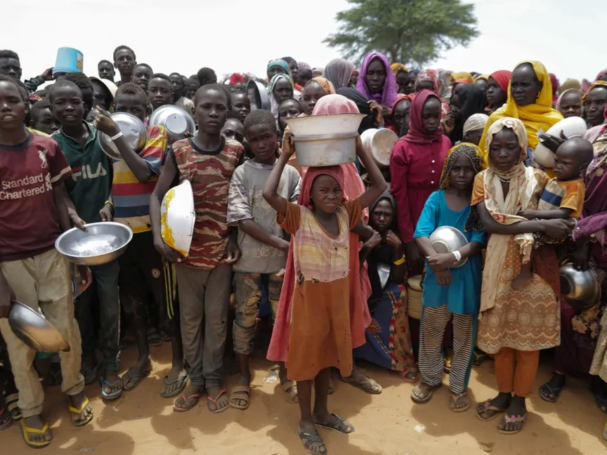 أطفال سودانيون فروا من الصراع في مدينة الجنينة بإقليم دارفور يصطفون لتلقي طعام من متطوعي الصليب الأحمر في مدينة أدري الحدودية مع تشاد. 25 يوليو 2023 - Reuters