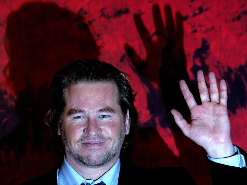 الممثل الأمريكي فال كيلمر يلوح للمصورين خلال جلسة تصوير في فندق بوسط، روما، 10 يناير 2005. - REUTERS