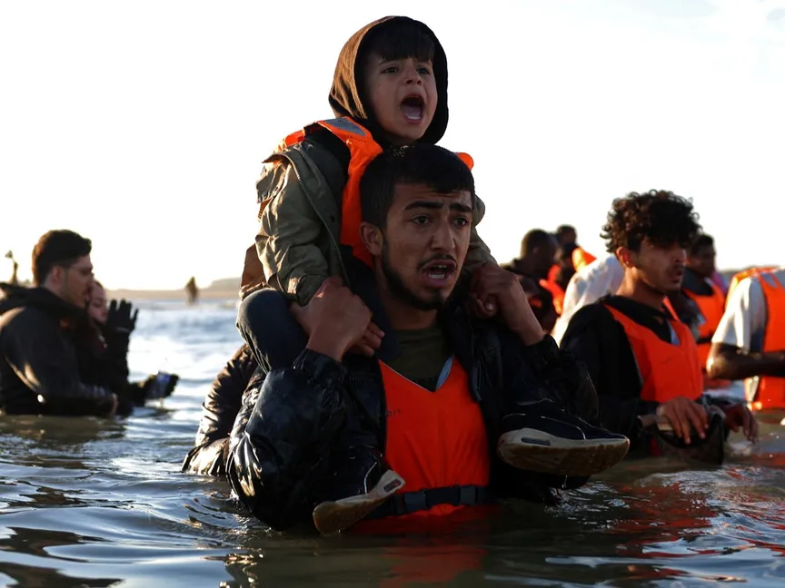 مهاجرون يخوضون في مياه البحر في محاولة للصعود على متن زورق مطاطي يغادر ساحل شمال فرنسا للوصول إلى بريطانيا. 25 أغسطس 2025 - Reuters